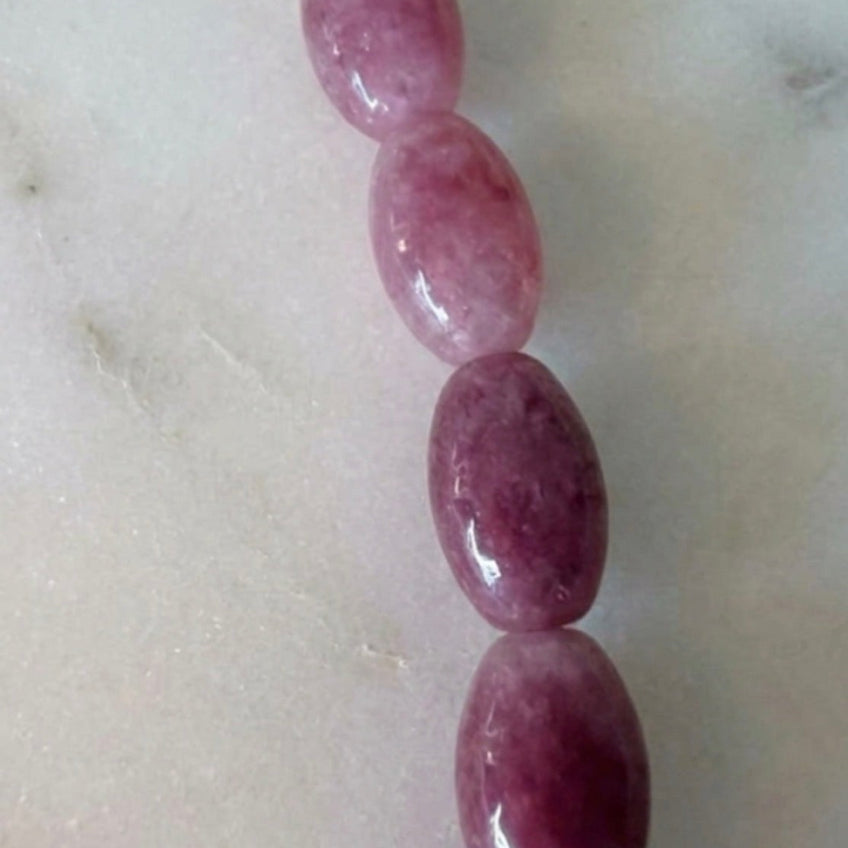 Détail perles ovales rhodonite fond marbre